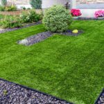 A beautiful artificial lawn in the front yard with nice flowers and shrubs surrounding it