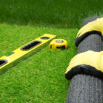 Man's hands spread an artificial turf roll